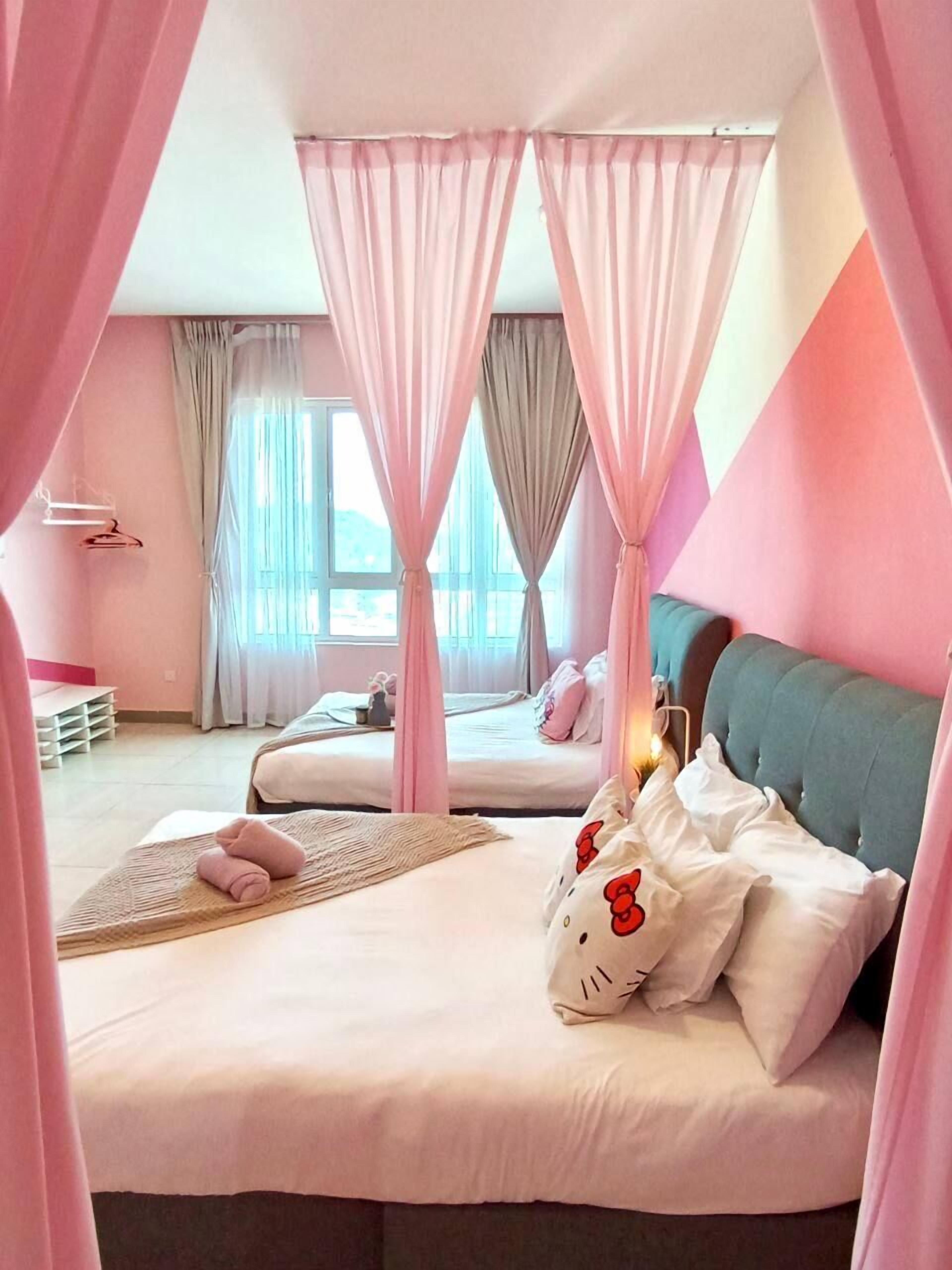 A pink-themed bedroom with a canopy bed, a second bed, and a bedside table with a Hello Kitty pillow.