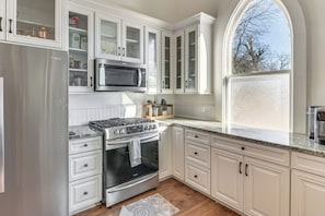 A kitchen with white cabinetry, a stainless steel refrigerator, a built-in microwave, and a gas stove. - 'The Sanctuary' in Historic Dtwn Staunton (Staunton)