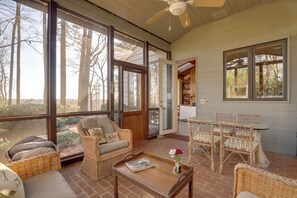 Ein gemütliches Zimmer mit Korbmöbeln, großen Fenstern und einem Deckenventilator.