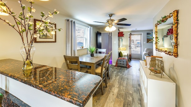A modern kitchen with granite countertops, wooden dining table, and chairs. There is a ceiling fan, a vase with branches, and a mirror on the wall. - Pet Friendly, Private! Multi-Level Brookline Home (Pittsburgh)
