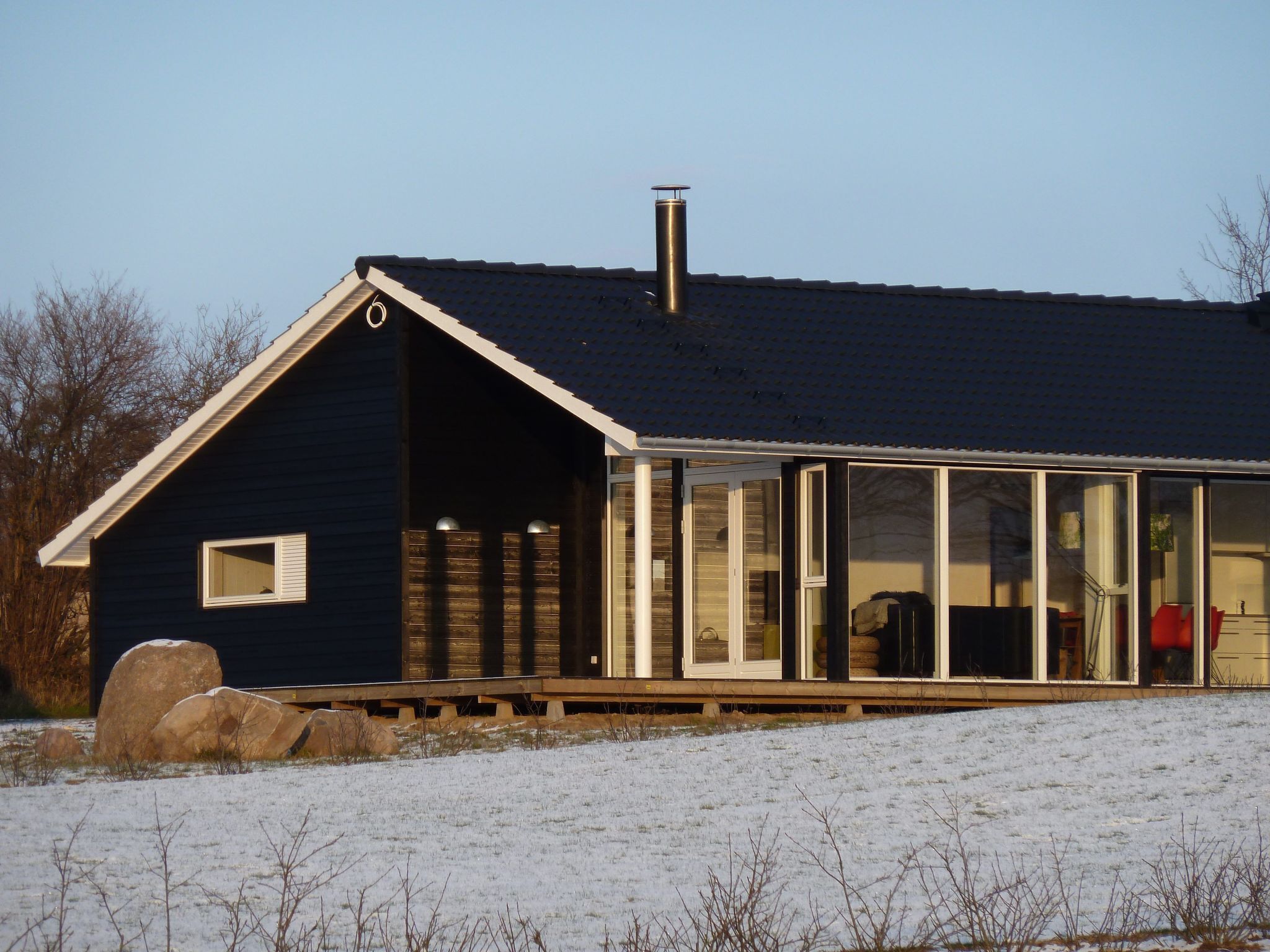 Et hus med mørkt ydre, en stor skorsten og en glasindhegnet veranda.