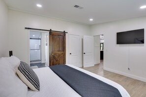 Une chambre à coucher avec un lit, une télévision et une porte coulissante donnant sur une salle de bain.