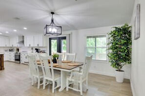 A modern kitchen with white cabinetry, a dining table with chairs, a chandelier, and a potted plant. - Hike & Fish! Tyler Family Home 11 Mi to State Park (Tyler)