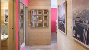 Ein Flur mit Holzwänden, einer roten Akzentwand und einer Wand mit Spiegeln und geometrischen Mustern.
