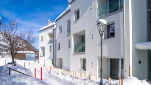 Ein modernes Gebäude mit vielen Fenstern und Balkonen, umgeben von Schnee.