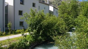 Ein Gebäude mit einer Steinmauer und einem kleinen Bach davor.