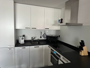 Eine moderne Küche mit weißen Schränken, einer schwarzen Arbeitsplatte, einer Mikrowelle, einem Toaster und einem Spülbecken.