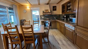 Una cocina moderna con armarios de madera, una mesa de comedor con sillas y un ventanal grande.