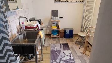 A compact kitchen with a sink, a small countertop, and a window with a beach mural.
