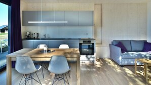 A modern kitchen with a wooden dining table, grey chairs, and a built-in oven. - Tinyhaus Adam by Interhome (Freiamt)