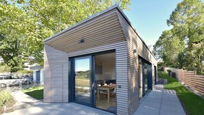 A modern house with a large sliding glass door leading to an outdoor dining area. - Tinyhaus Adam by Interhome (Freiamt)