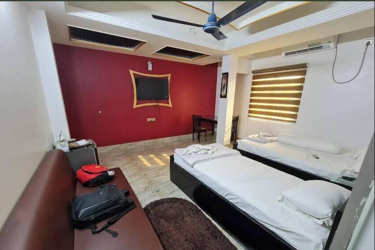 Ein Hotelzimmer mit Bett, Schreibtisch, Stuhl, Deckenventilator und einem Fenster mit Jalousien.