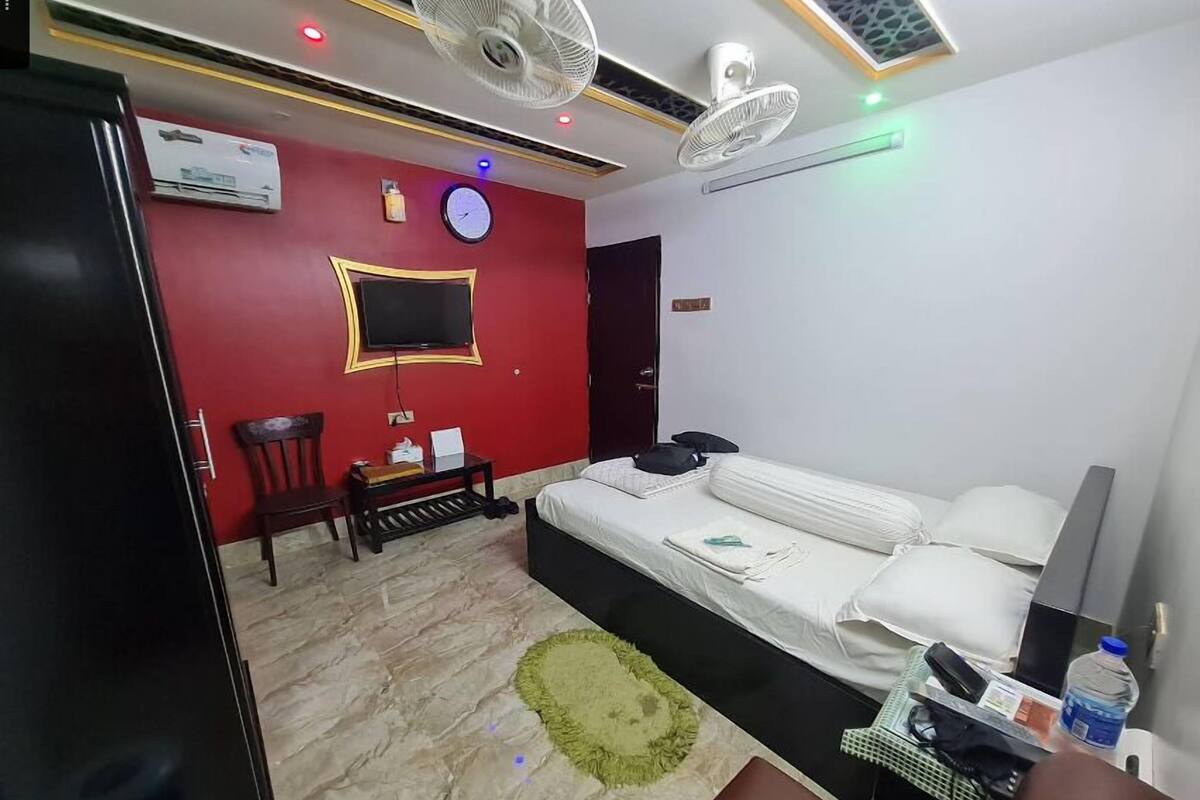 Ein Hotelzimmer mit Bett, Fernseher, Schreibtisch und Stuhl.