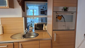 A compact kitchen with a sink, a microwave, and a refrigerator. - ApartmentDonaustrand by Interhome (Leiben)