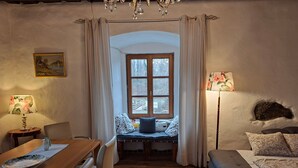 A cozy room with a wooden dining table, a sofa, and a window with curtains. - ApartmentDonaustrand by Interhome (Leiben)