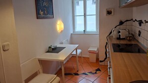 A compact kitchen with a white table, a chair, a window, and a tiled backsplash. - ApartmentDonaustrand by Interhome (Leiben)