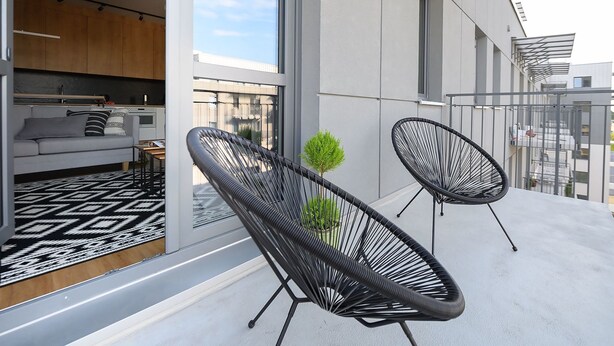 Un appartement moderne doté d’un balcon, de grandes fenêtres et d’un coin cuisine.