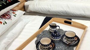 Een slaapkamer met een houten hoofdbord, een bed met wit beddengoed, een houten kledingkast en een dienblad met theeservies.