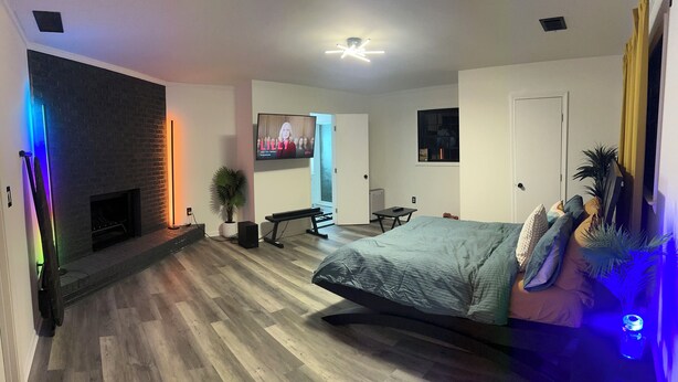Una camera da letto moderna con un letto, un camino, una TV e una ventola a soffitto.