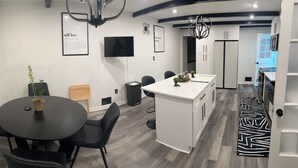 Una cucina moderna con mobili bianchi, un'isola con piano di lavoro nero e un tappeto a motivi bianchi e neri.