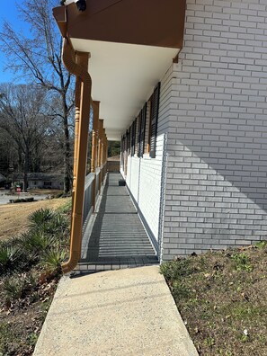 A covered walkway with a brick wall on one side and a wooden structure on the other. - Spacious Home Airport 10 Min (East Point)