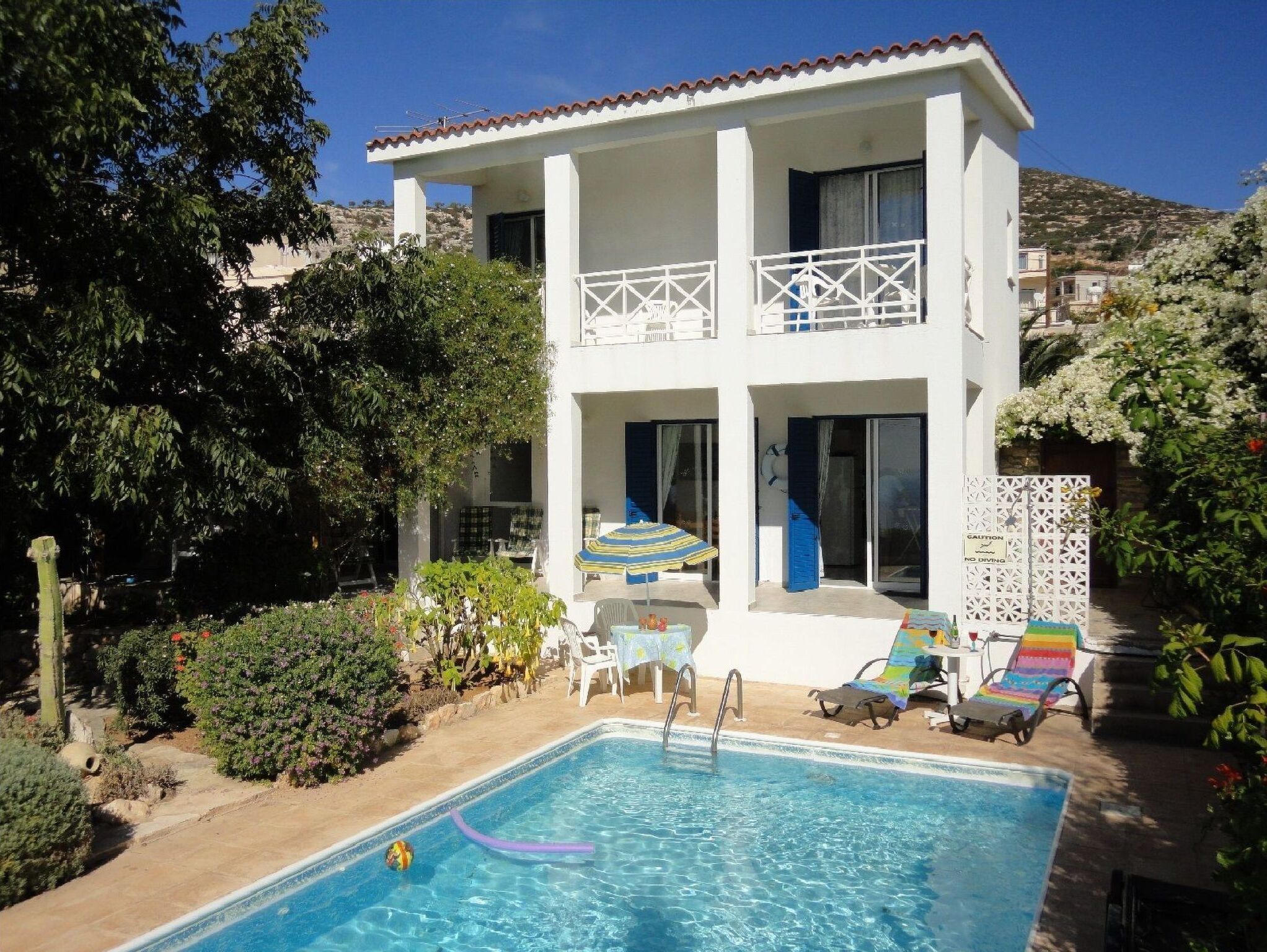 A two-story building with a swimming pool, outdoor seating, and a balcony.