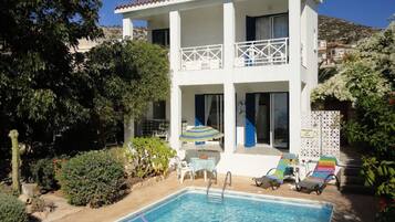 A two-story building with a swimming pool, outdoor seating, and a balcony.
