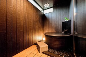 Ein modernes Badezimmer mit Holzverkleidung, einer großen Badewanne und einer kleinen Pflanze.