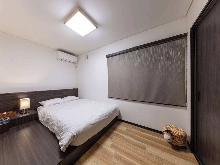A bedroom with a bed, bedside table, lamp, and a small animal figure.
