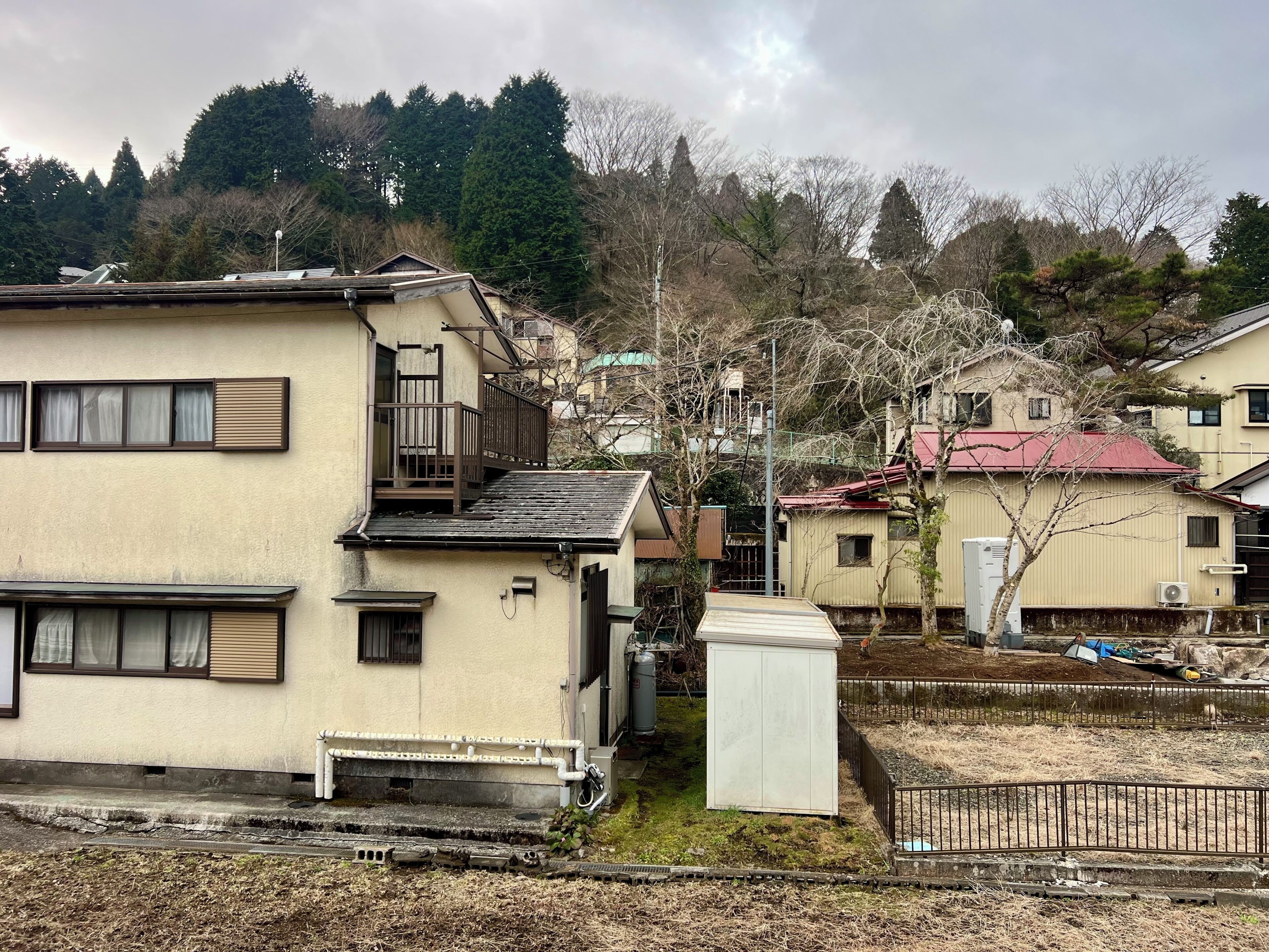 A residential area with houses, a small utility shed, and a fenced yard.
