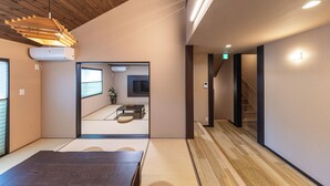 A modern interior with a wooden ceiling, a dining area with tatami mats, a television, and a staircase. - Hakone Mori No Sato (Hakone)