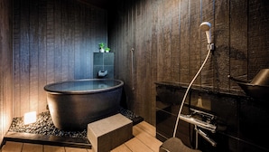 A modern bathroom with a large bathtub, a small shelf with plants, and a shower area. - Hakone Mori No Sato (Hakone)