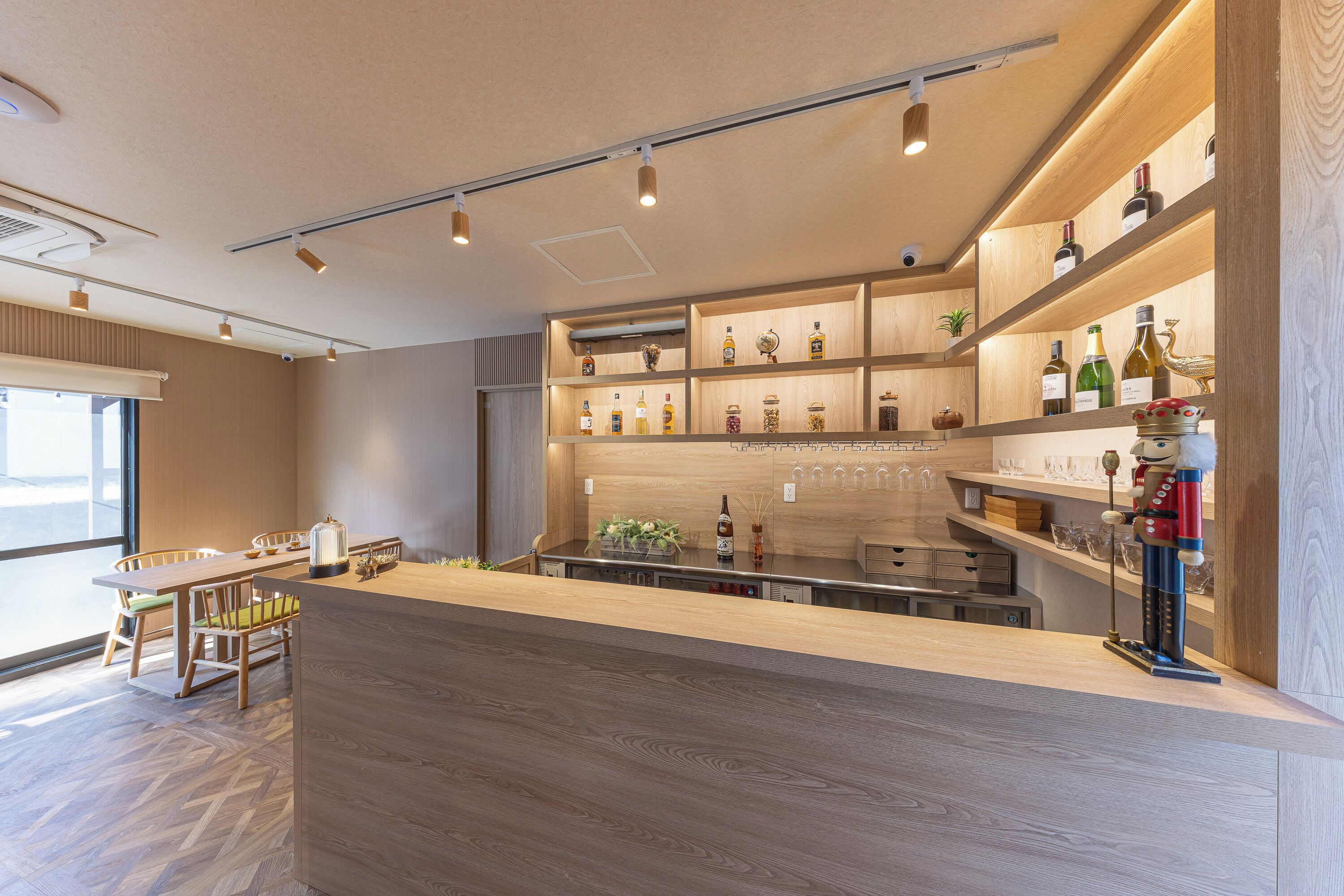 A modern bar area with wooden shelves, a counter, and seating.