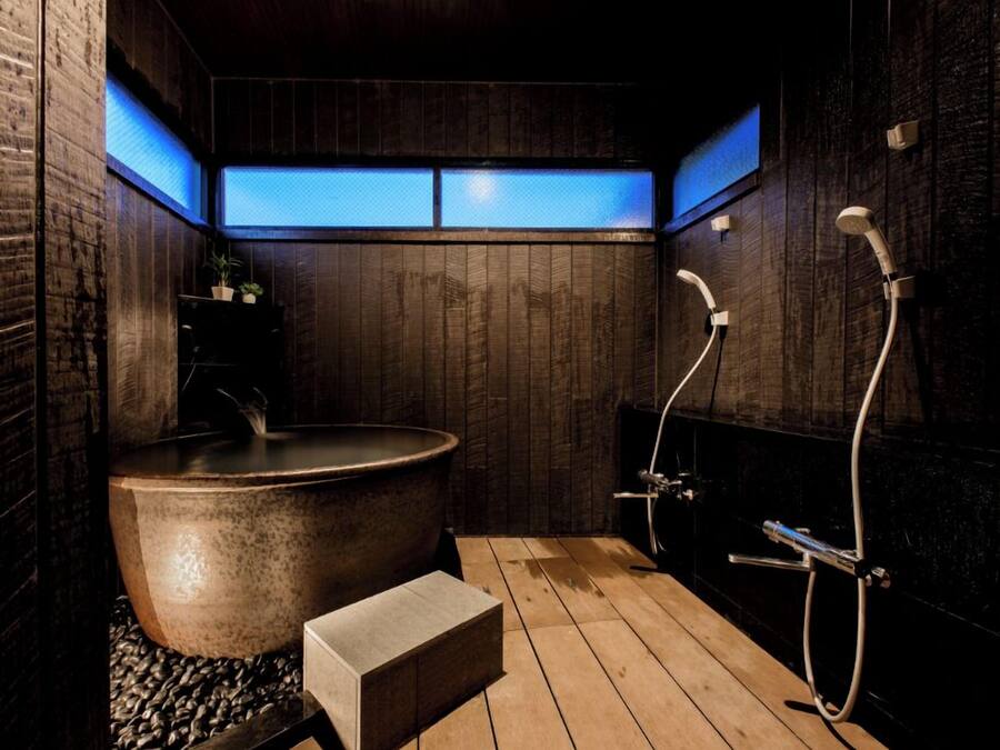 Une salle de bain moderne dotée d’une grande baignoire sur pieds, d’un espace douche et de panneaux muraux en bois.