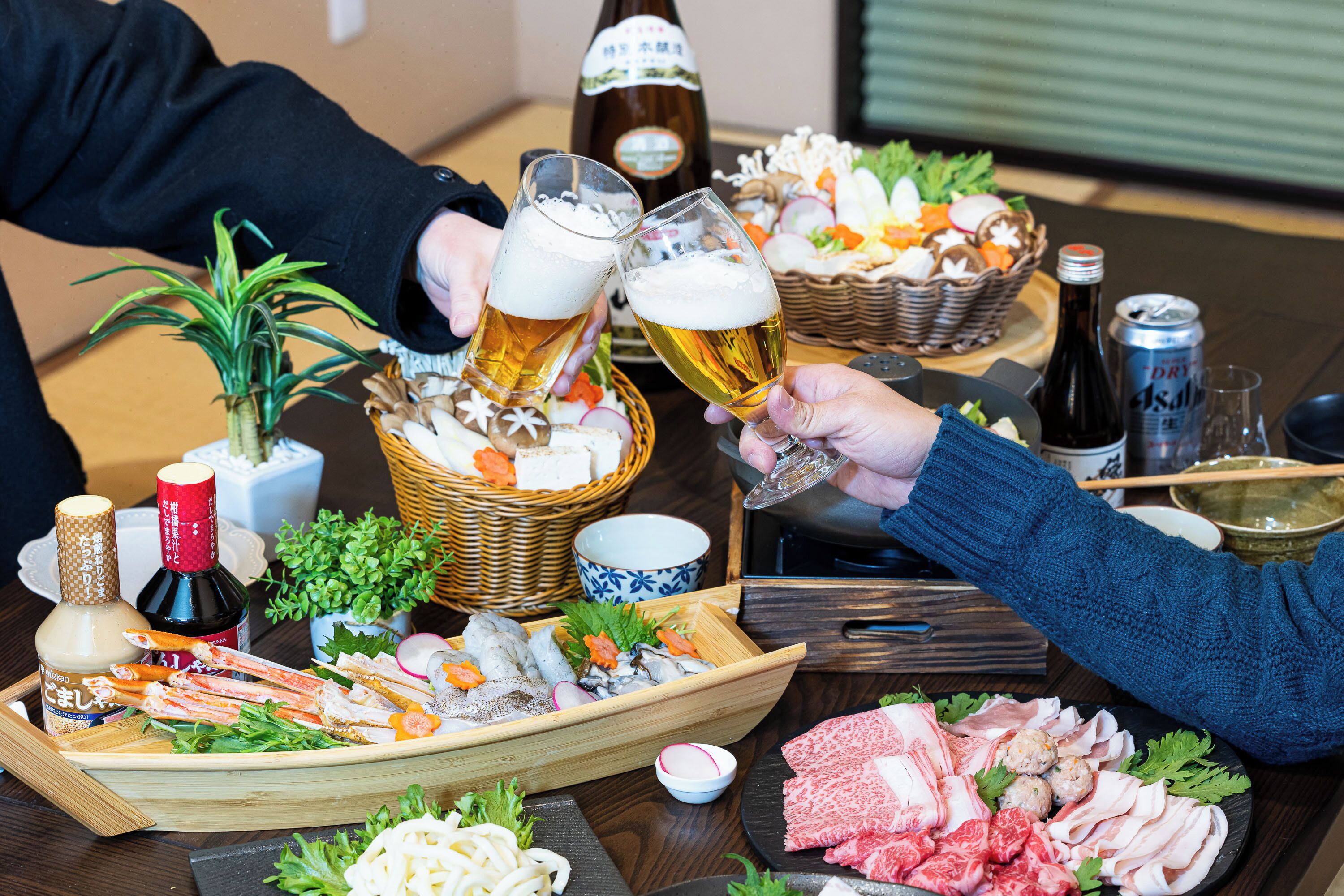 Una mesa de comedor con diferentes alimentos y bebidas, incluyendo una botella de sake, una lata de cerveza y una botella de salsa de soja.