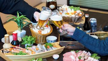 Una mesa de comedor con diferentes alimentos y bebidas, incluyendo una botella de sake, una lata de cerveza y una botella de salsa de soja.