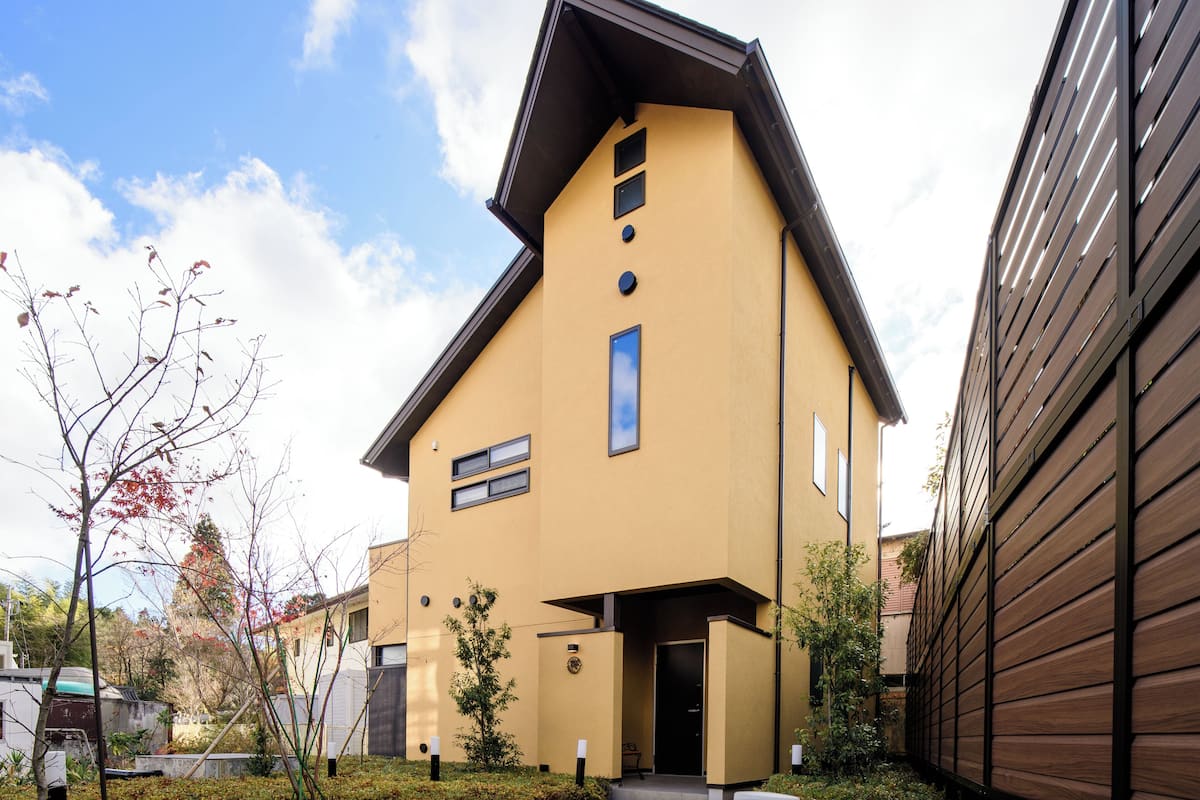 Un edificio moderno de dos pisos con techo plano y fachada amarilla.