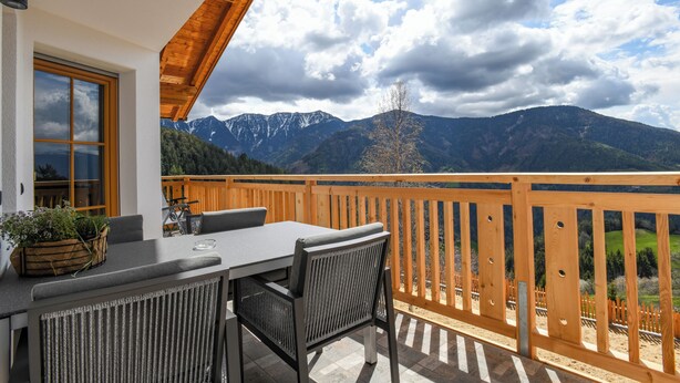 A balcony with a table and chairs, overlooking a mountainous landscape. - "Nock" | ZumMoarSepp - Holiday apartment in the Villnöss Valley (Trentino-Alto Adige)