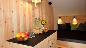 A wooden interior with a black countertop, a wooden cabinet, a bed with pillows, and a hanging light fixture. - "Nock" | ZumMoarSepp - Holiday apartment in the Villnöss Valley (Trentino-Alto Adige)