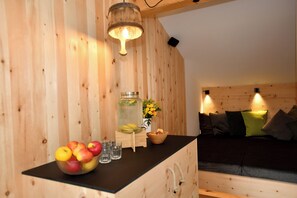 Ein Holzinbau mit einer schwarzen Arbeitsplatte, einem Holzschrank, einem Bett mit Kissen und einer Hängelampe.