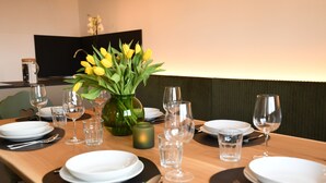 A dining table set with plates, cutlery, and glasses, with a vase of yellow flowers in the center. - "Nock" | ZumMoarSepp - Holiday apartment in the Villnöss Valley (Trentino-Alto Adige)