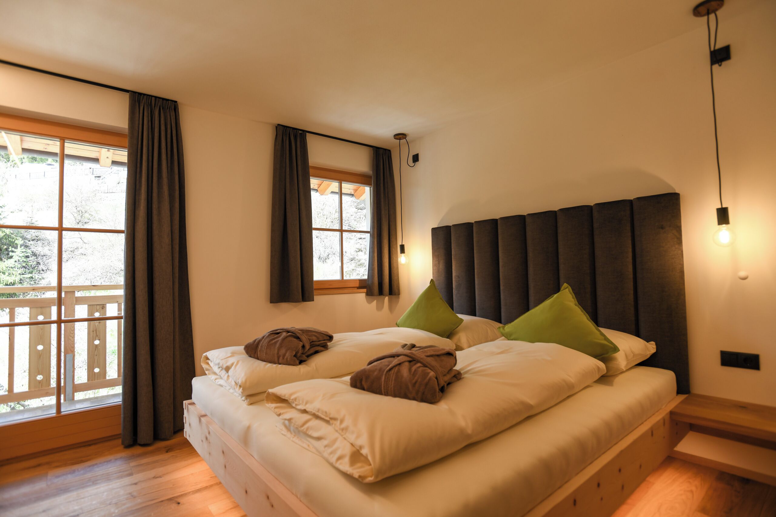 Ein Schlafzimmer mit einem großen Bett, zwei Kissen, einem Kopfteil, einem Nachttisch und einem Fenster mit Vorhängen.