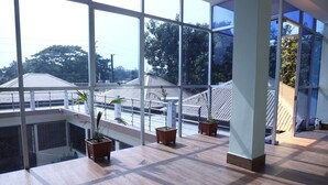 A spacious room with large windows, wooden flooring, and potted plants on a balcony. - Kishoreganj Haor Resort (Kishoreganj Sadar)