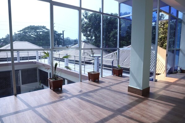 A spacious room with large windows, wooden flooring, and potted plants on a balcony. - Kishoreganj Haor Resort (Kishoreganj Sadar)