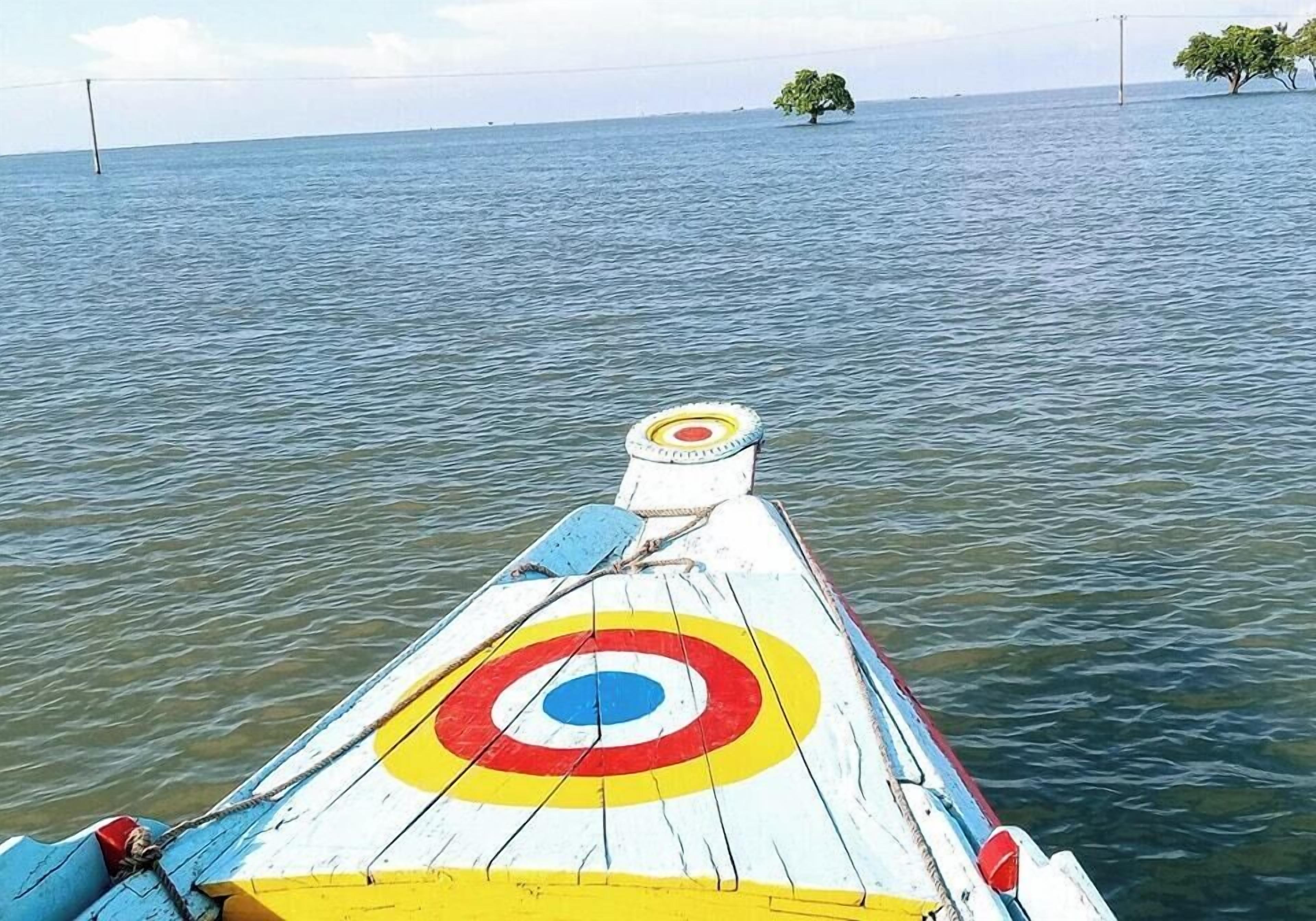A boat with a colorful target design on its side, floating on calm water.
