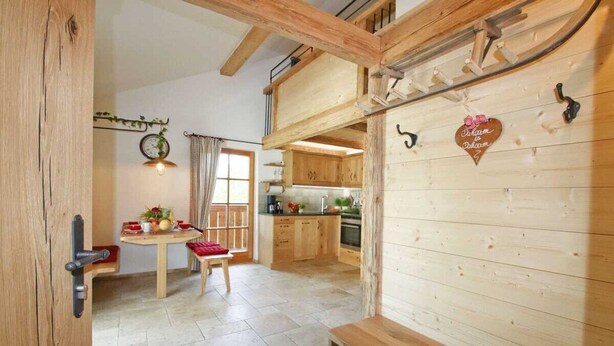A rustic wooden interior with a dining area, kitchen, and a loft space. - Vacation apartment Barbara (Chieming)