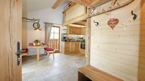 Un interior rústico de madera con comedor, cocina y un banco.