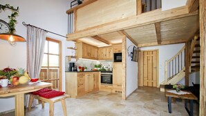Una cocina amplia con armarios de madera, un comedor con banco y una escalera que sube a un nivel superior.