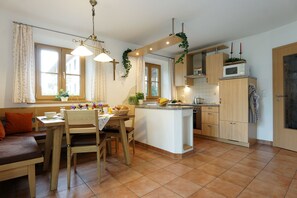 Eine Küche mit Kochinsel, Holzschränken und einer Essecke mit Bank und Tisch.