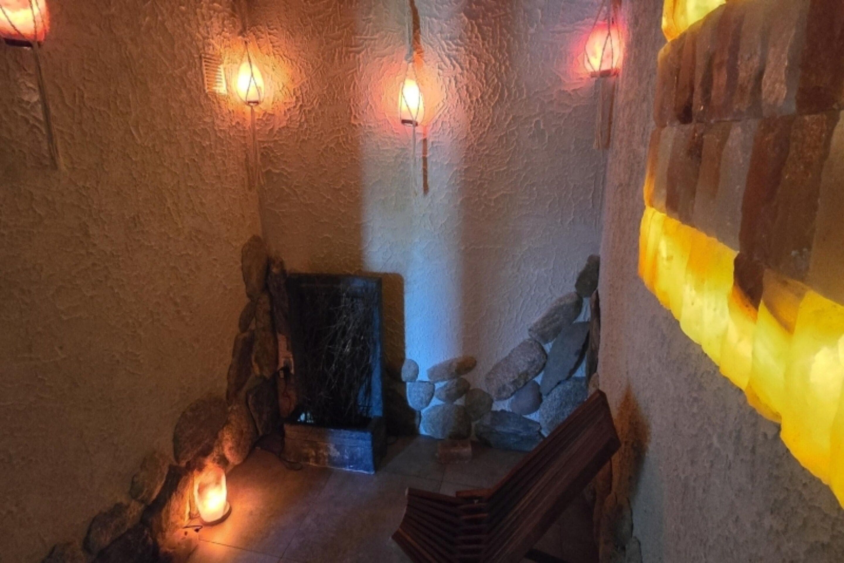 A stone-walled interior with a wooden bench, a stone fireplace, and wall-mounted lights.
